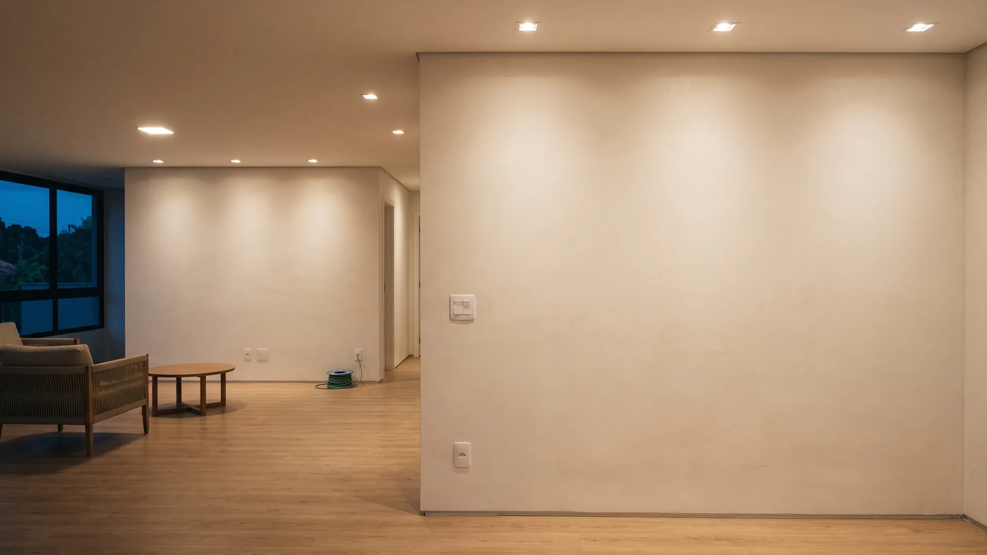 Sala de uma casa ao entardecer com as luzes de teto acesas e interruptor novo na parede