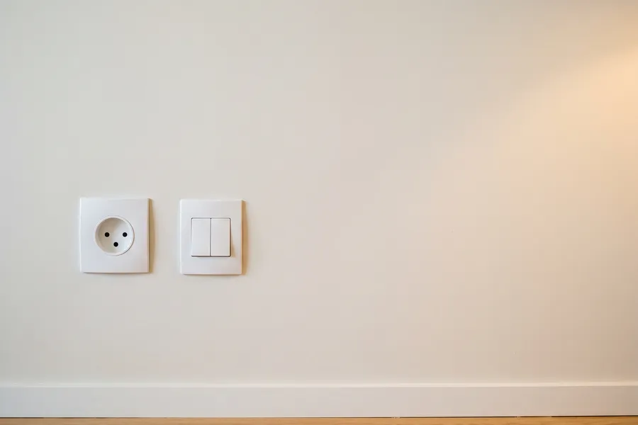 Tomada nova e interruptor de duas teclas instalados rente em parede pintada
